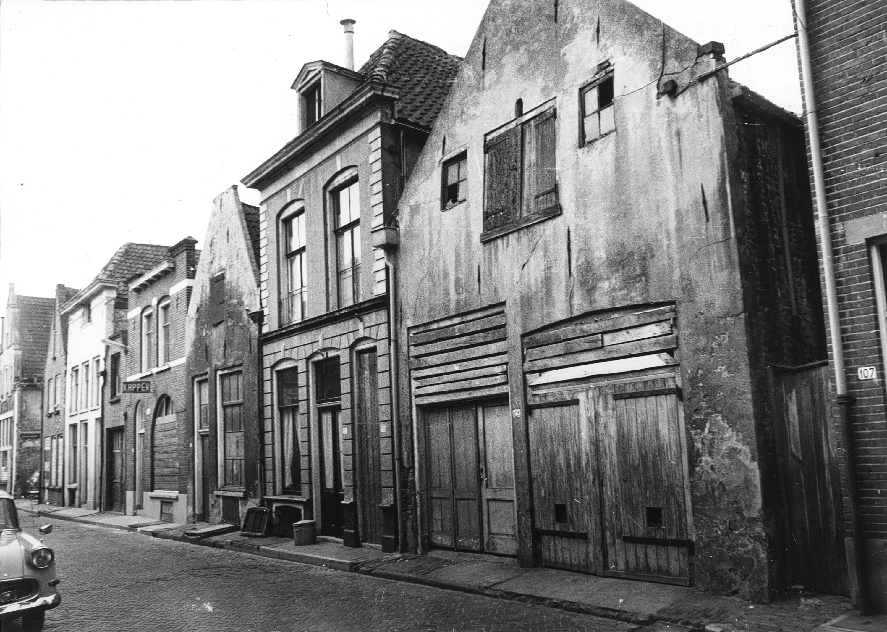 Boven de dichtgetimmerde pui is het uithangbord van de kapper nog zichtbaar